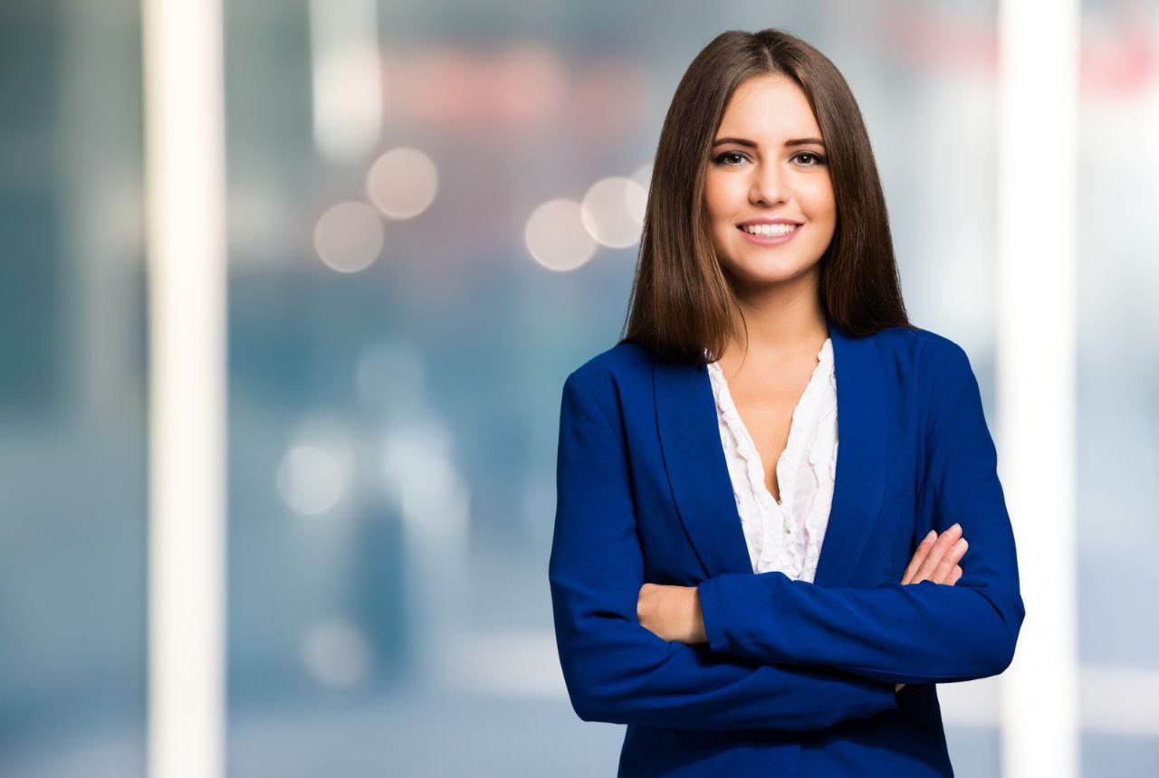 Professional businesswoman in blue blazer with arms crossed, representing Accessible ICT's commitment to excellence and professional service