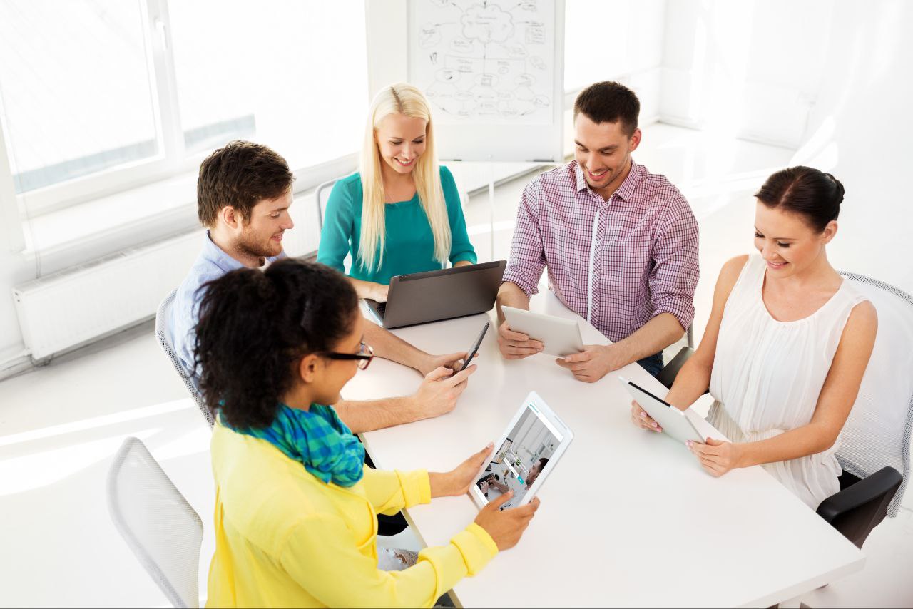 Diverse team of professionals collaborating with laptops and tablets in a modern office setting, representing the Accessible Consult platform's collaborative approach